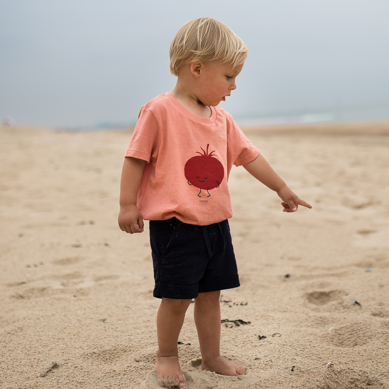 Kindje op strand met HONGRY Teddy Tomaat kinder kledij T-shirt  rose clay kleur..